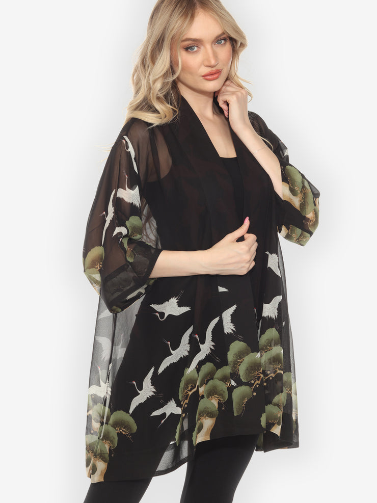Woman wearing a black dress with nature-themed print on a white background