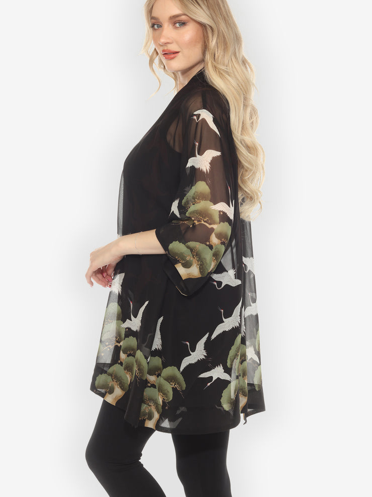 Woman wearing a black floral kimono-style garment on a white background