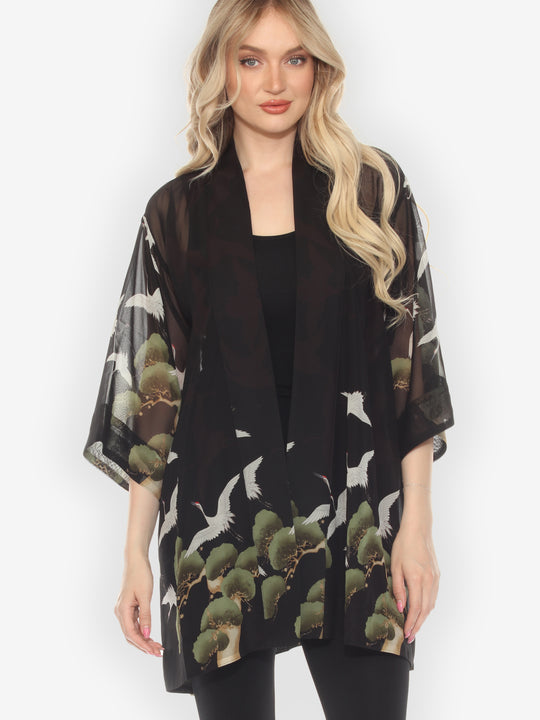 Woman wearing a black kimono-style garment with nature-themed design on a white background