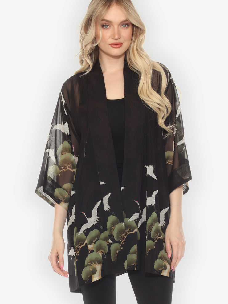 Woman wearing a black kimono-style garment with nature-themed design on a white background